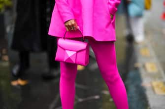 PARIS, FRANCE - OCTOBER 02: Yuwei Zhangzou wears a neon pink shoulder-off / long sleeves short dress, neon pink tights, a neon pink shiny leather handbag, outside Valentino, during Paris Fashion Week - Womenswear Spring/Summer 2023, on October 02, 2022 in Paris, France. (Photo by Edward Berthelot/Getty Images)