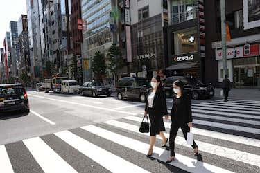 TOKYO, JAPAN - 2021/04/19: Businesswomen wearing face masks as a preventive measure against the spread of Covid-19 walk over a pedestrian crossing in the popular commercial district Ginza.
Tokyo's government considers calling a third state of emergency as Covid-19 cases rise again. (Photo by Stanislav Kogiku/SOPA Images/LightRocket via Getty Images)