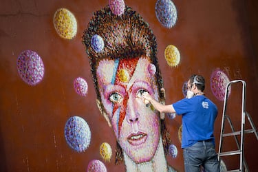 Australian street artist James Cochran, also known as Jimmy C, puts the finishing touches on a large 3D wall portrait of British musician David Bowie in Brixton, South London, on June 19, 2013. The artwork is based on the iconic cover for Bowies 1973 album, Aladdin Sane. AFP PHOTO/JUSTIN TALLIS        (Photo credit should read JUSTIN TALLIS/AFP via Getty Images)
