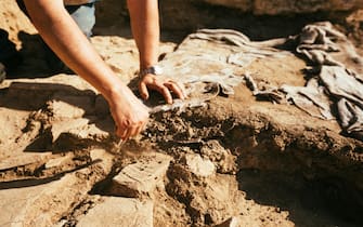 Close up of a man hand using a brush to Dust Pottery at Archaeological Site