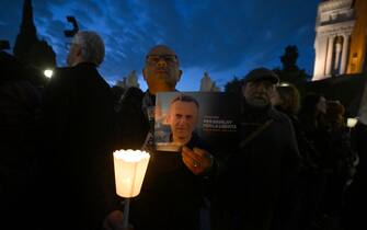 A man holds a portrait of Kremlin's critic Alexei Navalny during a vigil in his honor following is death, on February 19, 2024 in front of Rome's city hall. The poster reads 'for Navalny, for freedom'. Russia reported Navalny's death in an arctic prison on February 16, 2024 and his mother has been denied access to the body, enraging supporters who have accused authorities of trying to cover up Navalny's "murder". (Photo by Filippo MONTEFORTE / AFP) (Photo by FILIPPO MONTEFORTE/AFP via Getty Images)