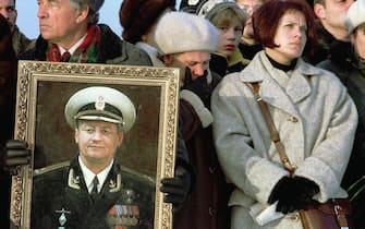 The widow of Lt Dmitry Kolesnikov, Olga, (3rd R), mourns 29 October 2000 during a memorial ceremony for the crew of the sunken Russian nuclear submarine Kursk at the ship's home port of Severomorsk, about 1500 km (940 miles) north of Moscow. Man at the left holds a portrait of the Kursk commander Capt. 1st rank Gennady Lyachin. Kolesnikov, an officer on the submarine Kursk, wrote his wife a mournful poem in the days before he went on the ship's final voyage, which ended when it sank 12 August 2000 in the Barents Sea.  (Photo credit should read -/AFP via Getty Images)