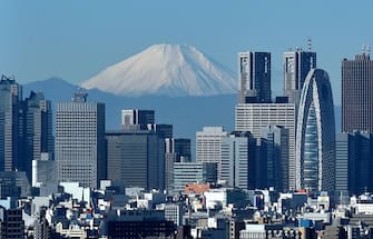 Japan's highest mountain, Mount Fuji (C) is seen behind the skyline of the Shinjuku area of Tokyo on December 6, 2014. Tokyo stocks closed at a seven-year high on December 5 -- extending their winning streak for a sixth straight day -- as a falling yen and oil prices continue to boost investor spirit.  AFP PHOTO / KAZUHIRO NOGI        (Photo credit should read KAZUHIRO NOGI/AFP via Getty Images)