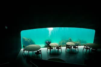 A diver cleans the outside of a viewing window of Under, a restaurant that is semi-submerged beneath the waters of the North Sea on May 2, 2019 in Lindesnes near Kristiansand, some 400 km south west of Oslo. - Under, a new restaurant that opened a few weeks ago in Lindesnes, serves up Poseiden's delicacies with a unique view, in an architectural showpiece that stretches five meters (15 feet) underwater. The restaurant is a 34-metre monolith designed by Norwegian firm Snohetta, known for its celebrated buildings such as the Oslo Opera and the 9/11 Memorial Pavilion in New York. (Photo by Jonathan NACKSTRAND / AFP) (Photo by JONATHAN NACKSTRAND/AFP via Getty Images)