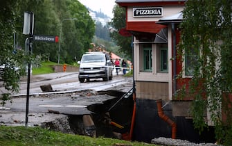 TOPSHOT - A destroyed street and a hole in the ground are seen outside a restaurant after the Susa River running through Are, northern Sweden, overflowed following heavy rainfall due to extreme weather 'Hans' on August 8, 2023. Large amounts of water an soil have rushed through the village causing damage to properties and roads. (Photo by Johan Axelsson / TT News Agency / AFP) / Sweden OUT (Photo by JOHAN AXELSSON/TT News Agency/AFP via Getty Images)