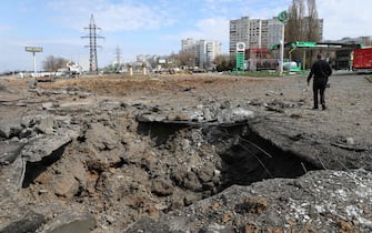 A man walks past a crater after missiles strike in Kharkiv on April 6, 2024, amid Russian invasion in Ukraine. (Photo by Anton Shtuka / AFP)