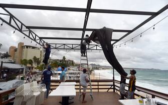 Restaurant employees put a protection fabric on a restaurant in front the Medano beach before the arrival of hurricane Hilary at Los Cabos resort in Baja California state, Mexico on August 18, 2023. Hurricane Hilary strengthened into a major storm in the Pacific on Friday and was expected to further intensify before approaching Mexico's Baja California peninsula over the weekend, forecasters said. (Photo by ALFREDO ESTRELLA / AFP) (Photo by ALFREDO ESTRELLA/AFP via Getty Images)