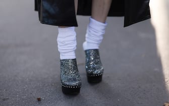 PARIS, FRANCE - OCTOBER 01: A fashion week guest seen wearing a long black leather coat and glitter clogs, outside Akris during Paris Fashion Week on October 01, 2022 in Paris, France. (Photo by Jeremy Moeller/Getty Images)