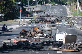 TOPSHOT - A street blocked by debris and burnt out items is seen following overnight unrest in the Magenta district of Noumea, France's Pacific territory of New Caledonia, on May 18, 2024. Hundreds of French security personnel tried to restore order in the Pacific island territory of New Caledonia on May 18, after a fifth night of riots, looting and unrest. (Photo by Delphine Mayeur / AFP) (Photo by DELPHINE MAYEUR/AFP via Getty Images)