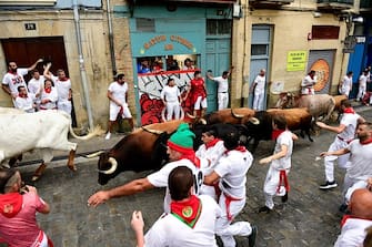 Participants run ahead of bulls during the first "encierro" (bull-run) of the San Fermin festival in Pamplona, northern Spain, on July 7, 2023. Thousands of people every year attend the week-long festival and its famous 'encierros': six bulls are released at 8:00 a.m. evey day to run from their corral to the bullring through the narrow streets of the old town over an 850 meters (yard) course while runners ahead of them try to stay close to the bulls without falling over or being gored. (Photo by ANDER GILLENEA / AFP) (Photo by ANDER GILLENEA/AFP via Getty Images)