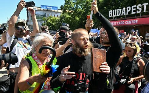 A Christian believer holds the Bible while taking part in the Budapest Pride march, on June 28, 2025 in Budapest, despite a governmental ban of the event. Hungary's Prime Minister had announced that police will not "break up" Saturday's Budapest Pride march despite issuing a ban, but warned attendees and organisers about the legal consequences. His ruling coalition amended laws and the constitution earlier this year to prohibit the annual celebration, advancing his widely condemned, years-long clampdown on LGBTQ rights in the name of "child protection". (Photo by Attila KISBENEDEK / AFP)