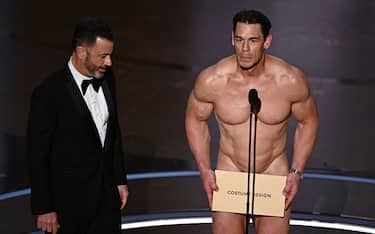 TV host Jimmy Kimmel (L) looks on as US actor John Cena (R) presents the award for Best Costume Design onstage during the 96th Annual Academy Awards at the Dolby Theatre in Hollywood, California on March 10, 2024. (Photo by Patrick T. Fallon / AFP) (Photo by PATRICK T. FALLON/AFP via Getty Images)
