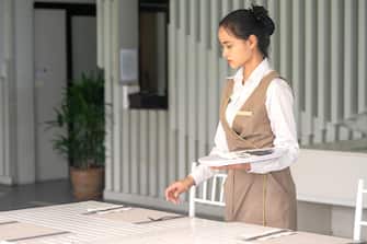 Waitress asian against empty tableware, table setting