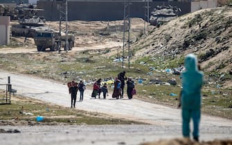epa11198260 Israeli tanks on patrol (background) as internally displaced Palestinians walk after the Israeli army told residents of the Hamad area in Khan Yunis to leave their homes and head towards Rafah, near the border with Egypt, southern Gaza Strip, 04 March 2024. The Israeli military stated on 04 March that a humanitarian evacuation corridor was established to allow civilians to exit the area. More than 30,500 Palestinians and over 1,300 Israelis have been killed, according to the Palestinian Health Ministry and the Israel Defense Forces (IDF), since Hamas militants launched an attack against Israel from the Gaza Strip on 07 October 2023, and the Israeli operations in Gaza and the West Bank which followed it.  EPA/MOHAMMED SABER