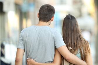 Back view portrait of a casual couple walking together on the street