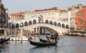 Venice, Veneto, Italy, Gondolas with tourists on the Grand Canal below the Rialto Bridge in evening light