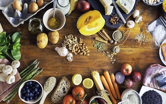 Colourful and healthy table composed with fruits and vegetables of many different types, meat, cheese, eggs, fish, spices and grains on wooden rustic wooden table, view from above