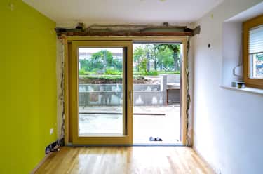 Replacing brick wall with glass sliding door in residential house. Construction renovation or remodelling project of inserting glass wall and new cons