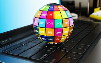 Globe with multi colored parts where domain names are written on laptop computer keyboard