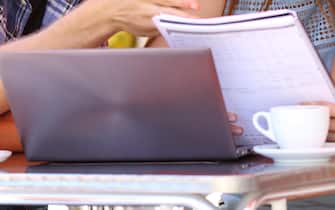 Three students studying and learning in a coffee shop with a laptop and notes