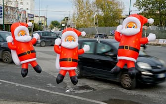 Pupazzi gonfiabili di Babbo Natale esposti da un venditore ambulante in un oincrocio del quartiere Secondigliano a Napoli tra passanti e automobilisti che indossano le mascherine, 4 dicembre 2020.
ANSA / CIRO FUSCO