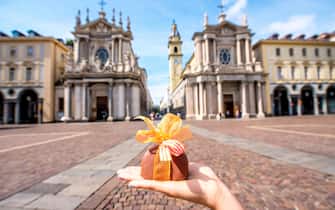 Holding italian chocolate with bow on Turin city background. Turin in Piedmont region in Italy is famous of its chocolate making