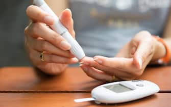 Close up of asian woman hands using lancet on finger to check blood sugar level by Glucose meter, Healthcare Medical and Check up, Medicine, diabetes, glycemia, health care and people concept