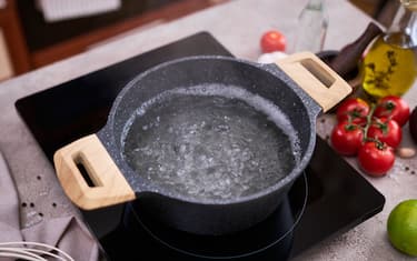 Boiling water in a cooking pot an a pan on a induction stove at domestic kitchen