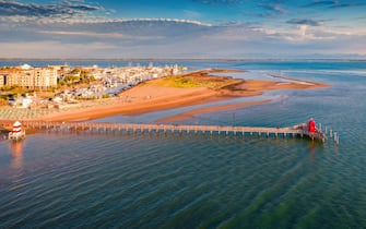 Panoramaic summer view from flying drone of Lignano Sabbiadoro town. Sunny outdoor scene of Adriatic coast of Italy with lighthous and old wooden pier