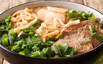 Lanzhou Beef Noodle Soup or Lanzhou Beef Lamian is a type of a very spicy soup of sliced beef, radish, red chili oil and herbs closeup in a bowl. horizontal