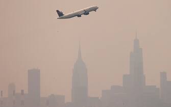 epa10680358 An airplane takes off from LaGuardia airport with buildings in Manhattan skyline in the background as smoke from wildfires burning in Canada continues to create unhealthy air quality conditions in New York, New York, USA, 08 June 2023. New York City continues to be under an air quality alert as result of the smoke, which is affecting large portions of the United States and causing flight delays around as well as ground stops due to poor visibility.  EPA/JUSTIN LANE