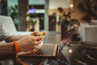 Teen boy's hands works on laptop sits in hotel's hall with Christmas decor