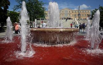 epa11312288 People walk past red colored water in the fountain in central Syntagma square, in front of the Greek parliament, after Pro-Palestinian demonstrators in a symbolic act poured red paint into the fountain, Athens, Greece, 01 May 2024. More than 34,550 Palestinians and over 1,455 Israelis have been killed, according to the Palestinian Health Ministry and the Israel Defense Forces (IDF), since Hamas militants launched an attack against Israel from the Gaza Strip on 07 October 2023, and the Israeli operations in Gaza and the West Bank which followed it.  EPA/ORESTIS PANAGIOTOU