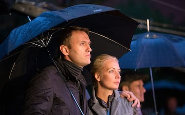 Alexey Navalny, Russian opposition leader, and his wife Yulia, shelter beneath an umbrella during a pre-election rally for Moscow's mayoral election in central Moscow, Russia, on Friday, Sept. 6, 2013. Navalny claimed the vote was rigged after an ally of Russian President Vladimir Putin narrowly won Moscow's mayoral election. Photographer: Andrey Rudakov/Bloomberg via Getty Images 