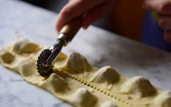 Separating pasta parcels using a pasta cutter wheel to make tortellini. One of the steps in the preparation of homemade tortellini, pasta parcels stuffed with beef, egg, parmesan cheese, in a kitchen in Italy