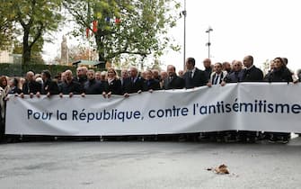 French Senate President Gerard Larcher (7thL), President of the French National Assembly Yael Braun-Pivet (6thL), surrounded by French Prime Minister Elisabeth Borne (C), France's former President Nicolas Sarkozy (5thL), France's former President Francois Hollande (9thL), Chief Rabbi of France Haim Korsia (L) and Bishop of Nanterre monseigneur Matthieu Rouge (L) stand behind a banner which reads as "For The Republic, Against anti-Semistism" during a march against anti-semitism in Paris, on November 12, 2023. Tens of thousands are expected to march Sunday in Paris against anti-Semitism amid bickering by political parties over who should take part and a surge in anti-Semitic incidents across France. Tensions have been rising in the French capital, home to large Jewish and Muslim communities, in the wake of the October 7 attack by Palestinian militant group Hamas on Israel, followed by a month of Israeli bombardment of the Gaza Strip. France has recorded nearly 12,250 anti-Semitic acts since the attack. National Assembly speaker Yael Braun-Pivet and Gerard Larcher, the Senate speaker, called on November 7 for a "general mobilisation" at the march against the upsurge in anti-Semitism. (Photo by Thomas SAMSON / AFP) (Photo by THOMAS SAMSON/AFP via Getty Images)