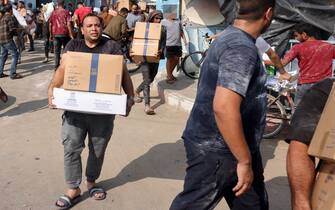 Palestinians storm a UN-run aid supply center, that distributes food to displaced families following Israel's call for more than one million residents in northern Gaza to move south for their safety, in Deir al-Balah on October 28, 2023, amid the ongoing battles between Israel and the Palestinian group Hamas. Thousands of civilians, both Palestinians and Israelis, have died since October 7, 2023, after Palestinian Hamas militants based in the Gaza Strip entered southern Israel in an unprecedented attack triggering a war declared by Israel on Hamas with retaliatory bombings on Gaza. (Photo by MOHAMMED ABED / AFP) / "The erroneous mention[s] appearing in the metadata of this photo by MOHAMMED ABED has been modified in AFP systems in the following manner: [Storm] instead of [Collect boxes and and bags from]. Please immediately remove the erroneous mention[s] from all your online services and delete it (them) from your servers. If you have been authorized by AFP to distribute it (them) to third parties, please ensure that the same actions are carried out by them. Failure to promptly comply with these instructions will entail liability on your part for any continued or post notification usage. Therefore we thank you very much for all your attention and prompt action. We are sorry for the inconvenience this notification may cause and remain at your disposal for any further information you may require." (Photo by MOHAMMED ABED/AFP via Getty Images)