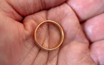 A lost and found gold ring, held in a cupped open palm of a hand