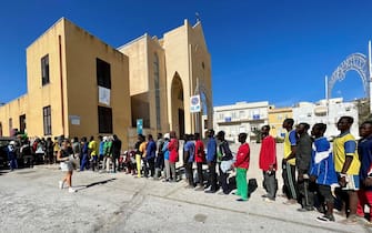 Alcuni migranti in fila per ricevere un pasto dalla Chiesa Parrocchiale di San Gerlando a Lampedusa, 14 settembre 2023. ANSA/ELIO DESIDERIO