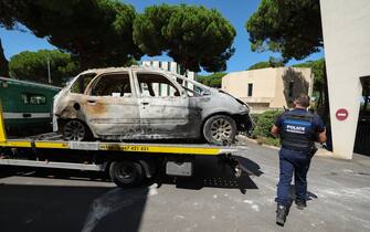 Attentato davanti sinagoga Francia A Police officer walks past a burnt car being moved on the bed of a towing vehicle in the seaside resort of La Grande Motte, near the city of Montpellier, southern France, on August 26, 2024, following the August 24, 2024 attack to the Beth Yaacov synagogue. Two vehicles were set on fire near the Beth Yaacov synagogue in La Grande-Motte, a seaside resort near Montpellier, on August 24, 2024, explained the French National Anti-Terrorist Prosecutor's Office, as well as two additional fires which targeted two of the building's access doors. After being on the run for fifteen hours, the suspected attacker of the synagogue was arrested in Nîmes, on August 24, 2024. (Photo by Pascal GUYOT / AFP) (Photo by PASCAL GUYOT/AFP via Getty Images)