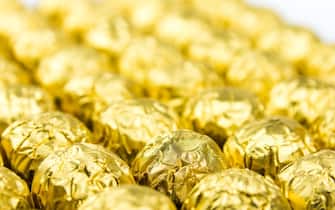 a lot of shiny golden chocolate wrapper in line on white background..