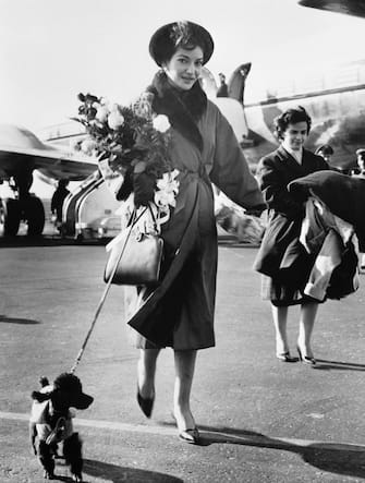 (Original Caption) Soprano Maria Callas leaves the field at Idlewild Airport after her arrival from Europe. With her is her pet dog, "Toy." Miss Callas, who made a triumphant appearance at the Paris Opera recently, is in NY for her scheduled appearance in the American Opera Society's presentation of Bellini's "Il Pirata."