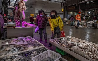 epa08957080 Woman wearing protective face masks chose fish at a market in a residential area of Wuhan, China, 22 January 2021. The day 23 January 2021 marks the one-year anniversary of the start of a strict 76-day lockdown of the Chinese city of Wuhan where the coronavirus was first discovered before spreading across the world into a deadly global pandemic.  EPA/ROMAN PILIPEY