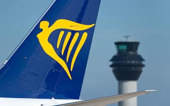 The tailfin of Ryanair Boeing 737-800 taxiing along the runway in front of the control tower at Manchester Airport.