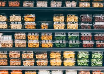 Store shelves with dried fruit, veggies, and nuts in a non-ecological packaging, non-branded. An image of plastic usage everywhere. Taking steps to a more sustainable lifestyle by utilizing reusable packaging and responsible business ideas.
