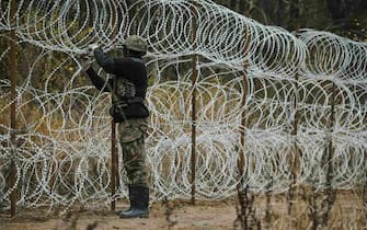 A Polish Army soldier connects coils of razor wire while constructing a fence along the Polish border, with the Russian enclave of Kaliningrad, near Zerdziny, Poland, on Saturday, Nov. 5, 2022. The Baltic region of Kaliningrad, cut off from the rest of Russia after the independence of the Baltic states in 1990, was in German hands for centuries until it was seized and annexed by the Soviet Union in 1945. Photographer: Damian Lemankski/Bloomberg