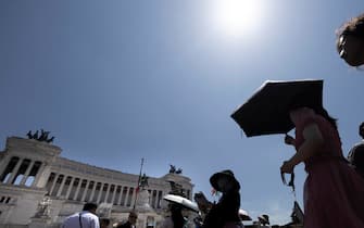 Turisti con gli ombrelli a piazza Venezia per proteggersi dal sole e dal caldo, Roma, 23 giugno 2023. 
ANSA/MASSIMO PERCOSSI