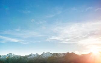 Low mountain range with expanse of sky and sun flare