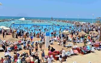 epa10739598 People gather on a beach amid a heatwave, in Rabat, Morocco, 11 July 2023. The Moroccan Directorate General of Meteorology said heatwaves are expected across the country until 14 July with temperatures forecasted to range between 37 and 47 degrees Celsius.  EPA/JALAL MORCHIDI