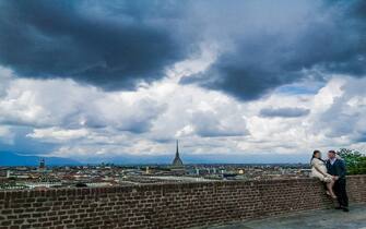 Nuvole nere minacciose di pioggia incombono sulla città e su una coppia di novelli sposi sul monte dei Cappuccini, Torino, 14 maggio 2021. ANSA/ TINO ROMANO